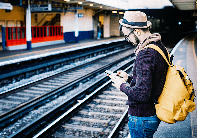 Man at Railway Station Typing on Phone