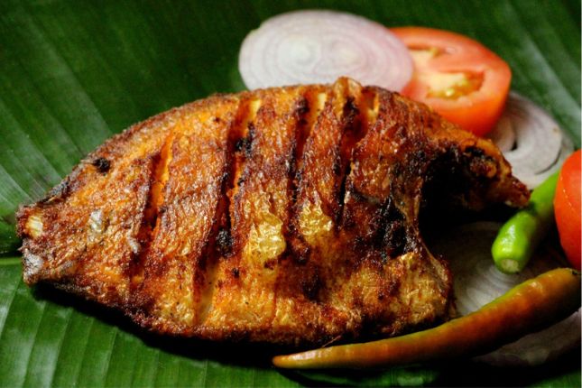 Grilled Karimeen Pollichathu wrapped in banana leaf – signature Kerala seafood delicacy